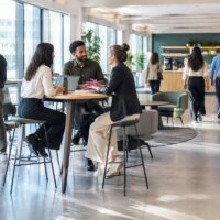 Salariés alternant travail assis, réunion debout et déplacements dans un bureau aménagé